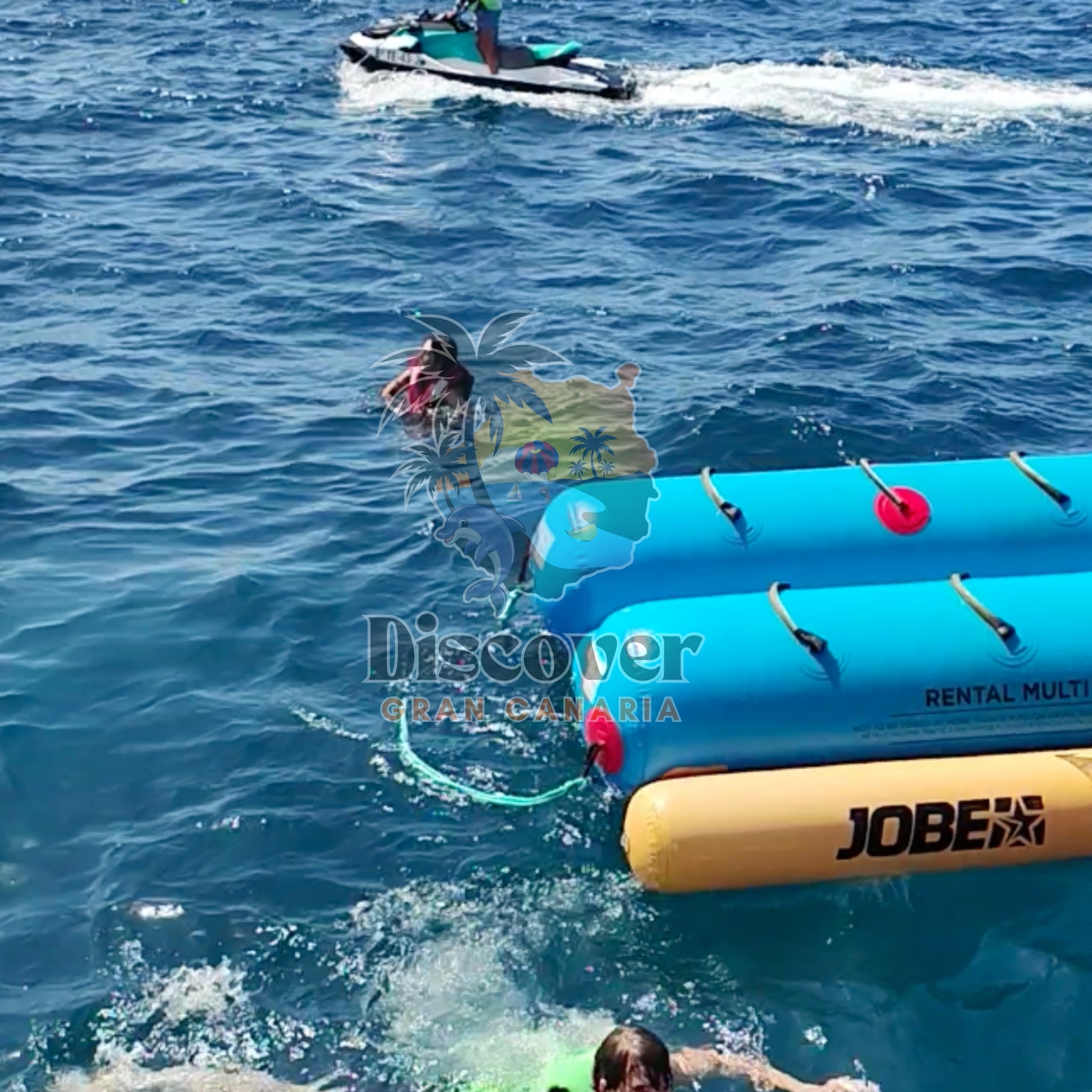 Two inflatable rafts in the water with a person swimming and another on a jet ski in the background.