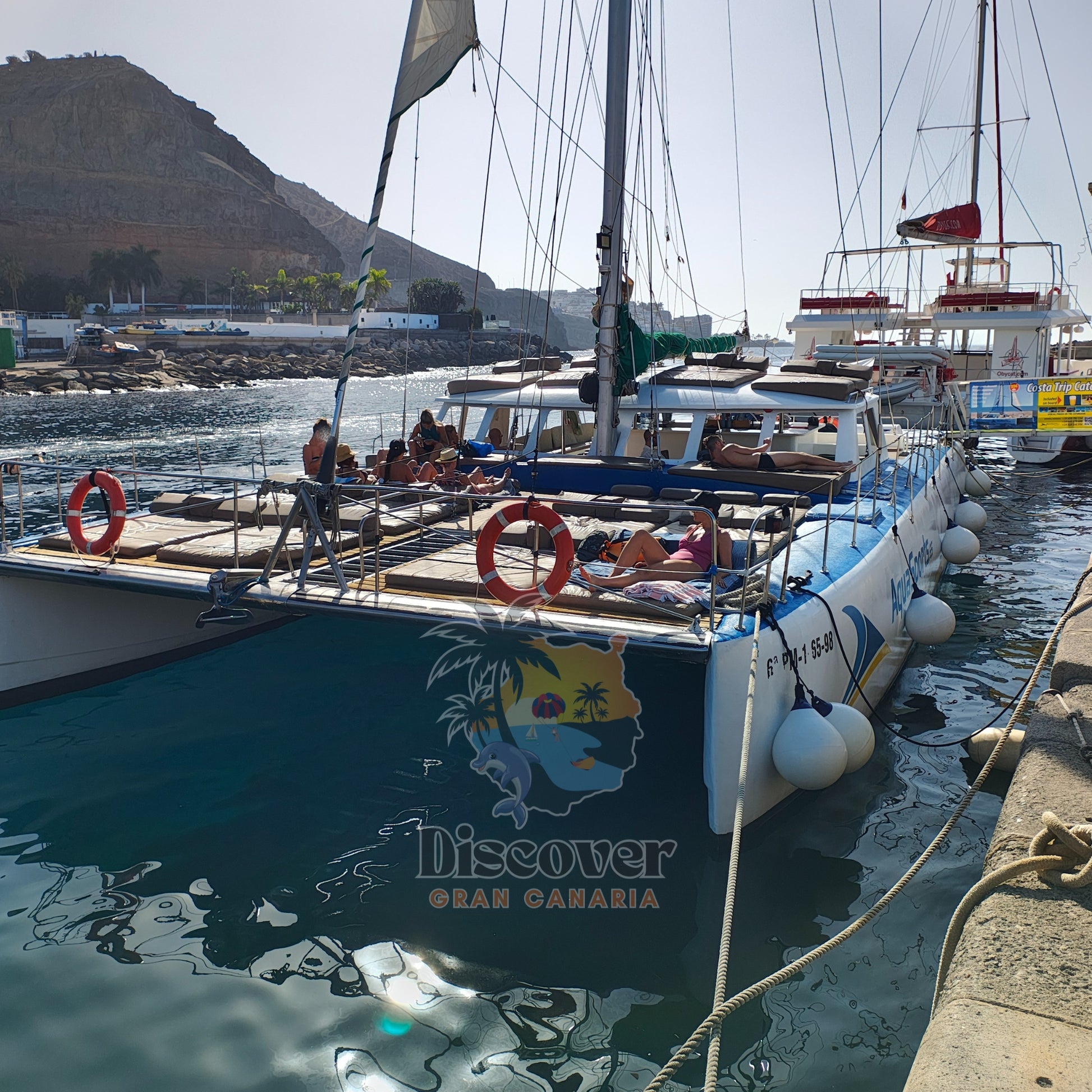 Catamaran tour with 'Discover Gran Canaria' branding docked at a harbor.