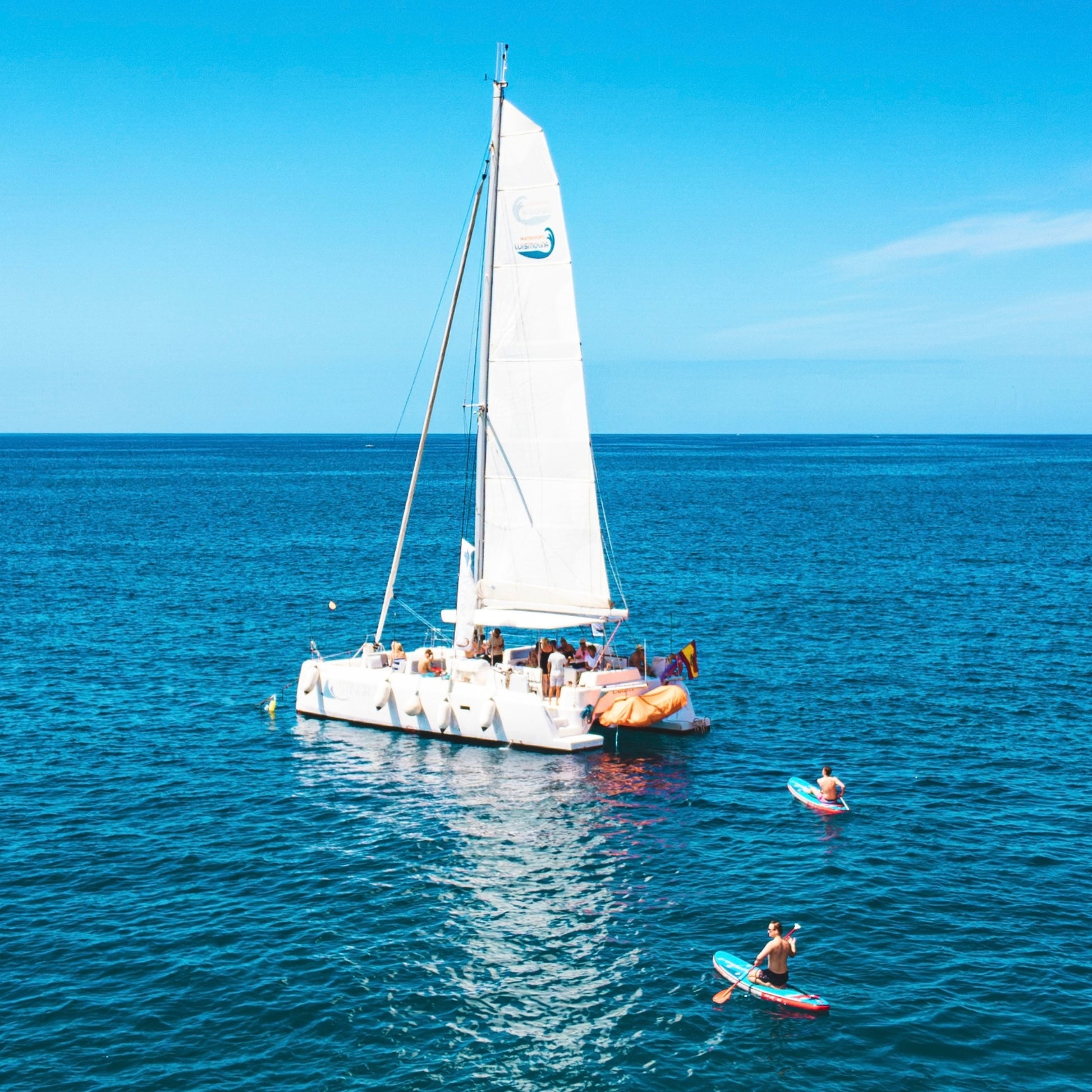 stingray  anchored on a clear blue sea with people around
