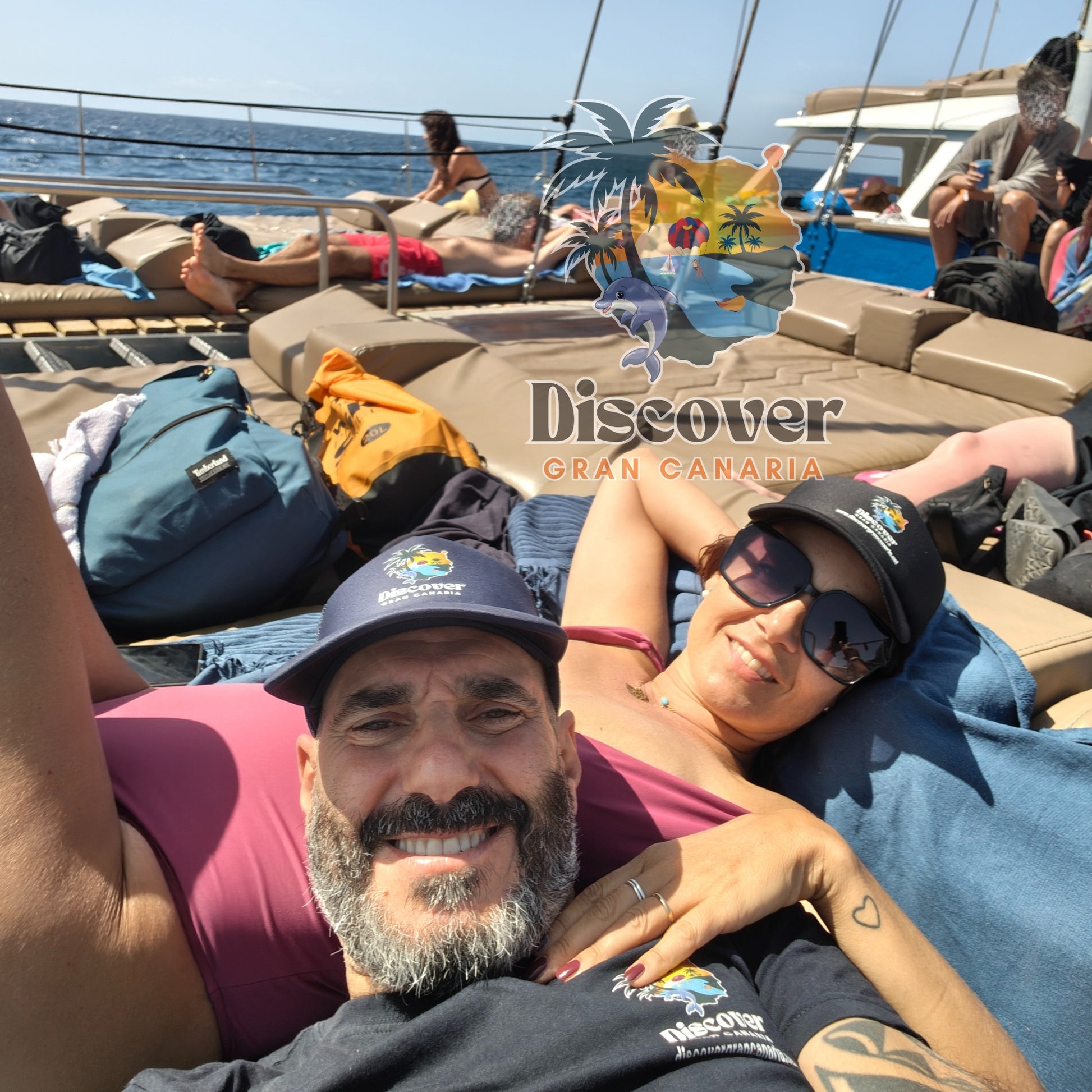 Two people lying on a boat with 'Discover Gran Canaria' branding in the background.