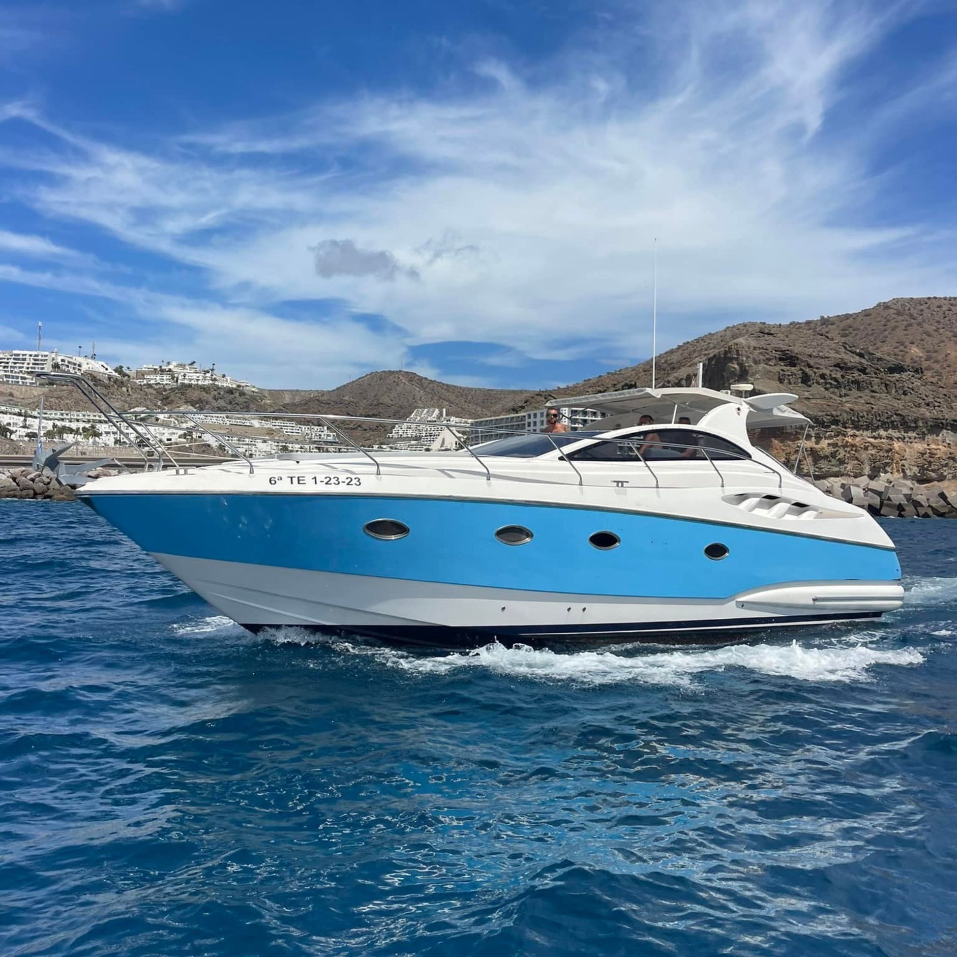 Blue and white yacht on the water with a scenic background