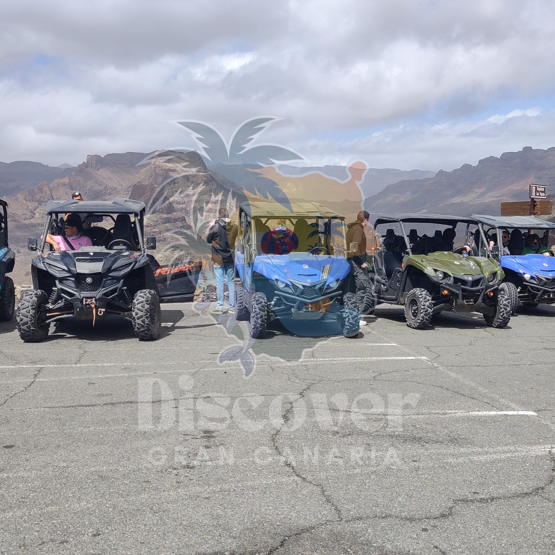 Group of all-terrain buggies  in a parking lot with mountains in the background, featuring 'Discover Gran Canaria' logo.