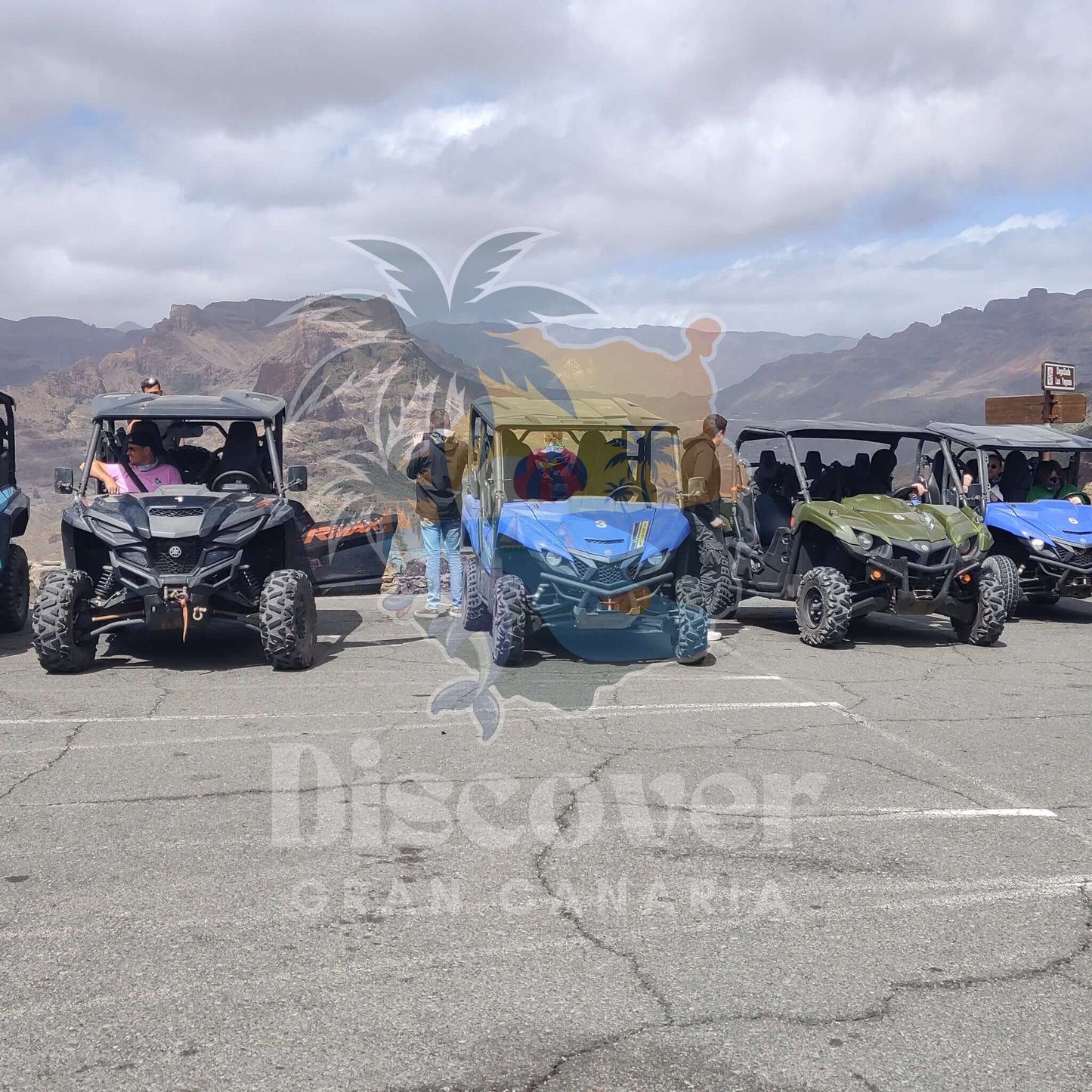 Group of all-terrain buggies in a parking lot with mountains in the background, featuring 'Discover Gran Canaria' logo.