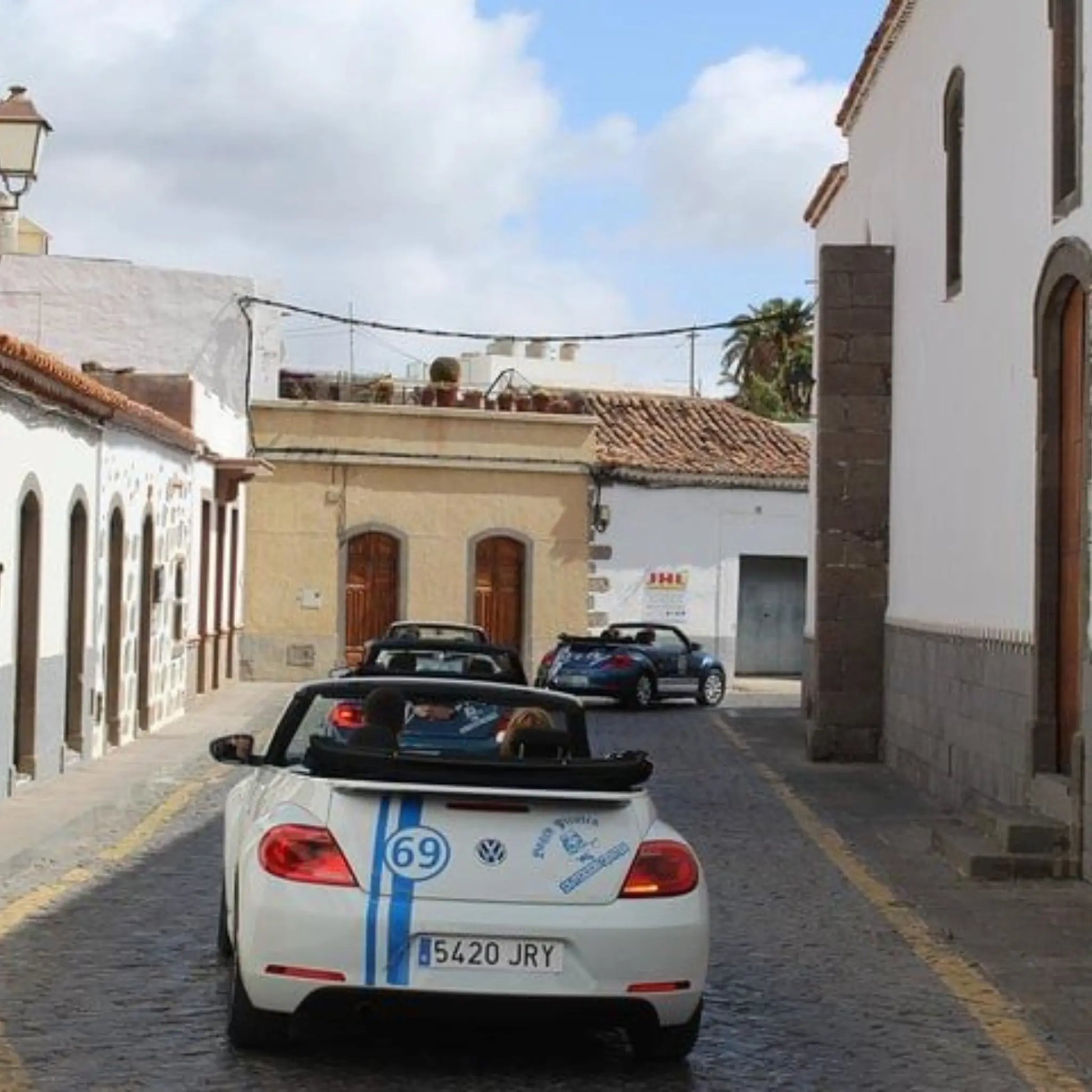 White convertible car with racing decals on a narrow street in Ingenio, Gran Canaria