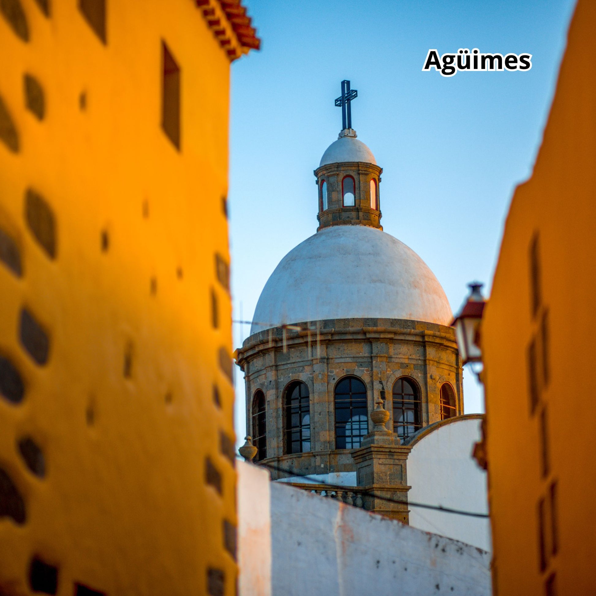 Cathedral dome with a cross between two buildings, labeled 'Agüimes'.
