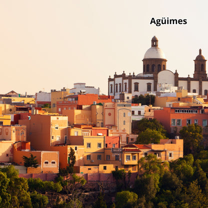Cityscape of Agüimes with colorful buildings and a prominent church.