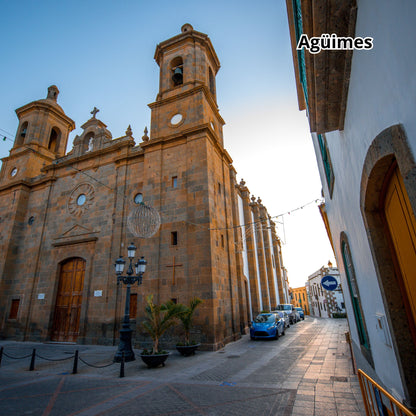 Large stone building of the ayuntamiento with a bell tower on a street in Agüimes