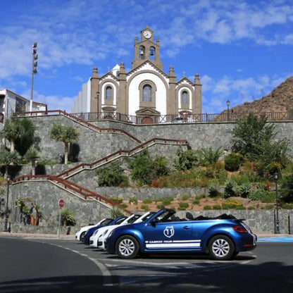 Blue convertible car with white stripes parked on a street in front of the church of Ingenio village in Gran Canaria.