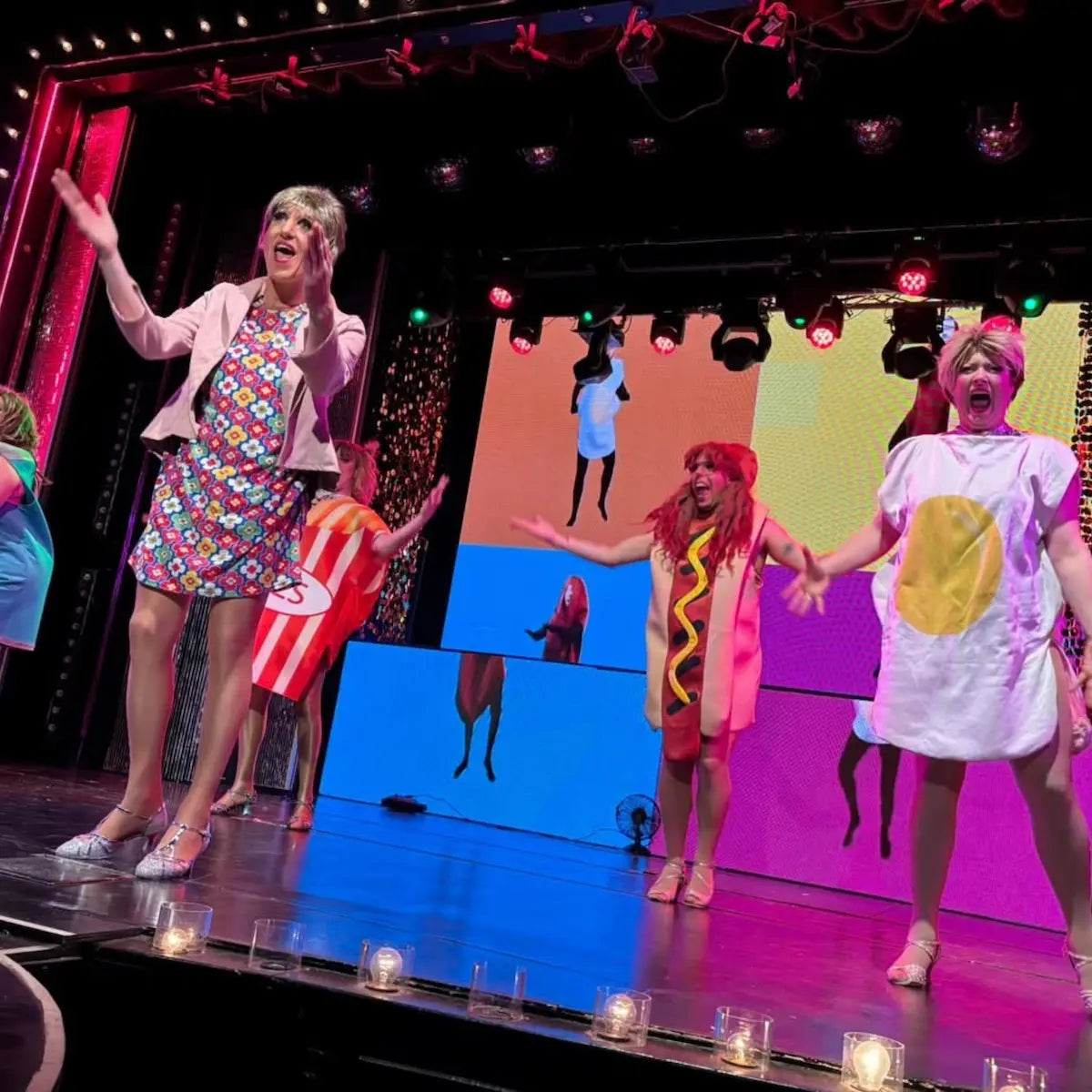 Stage performance with performers in colorful costumes on a stage with a colorful backdrop.