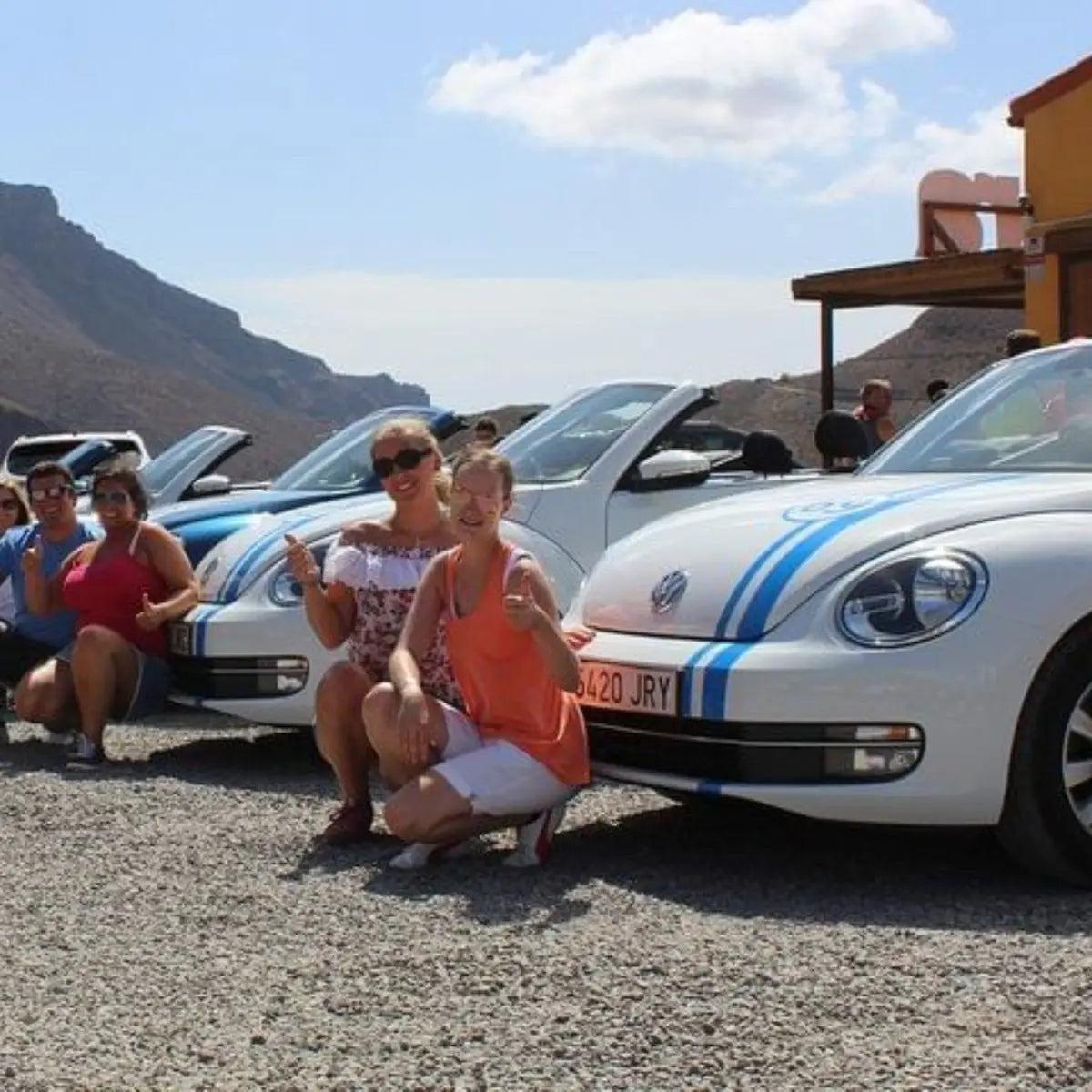 Group of people posing with a white Volkswagen Beetle parked at the aloe vera farm in Gran Canaria