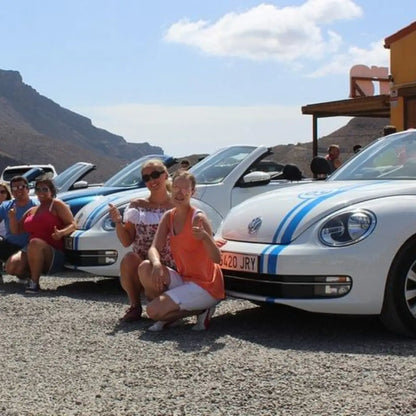 Group of people posing with a white Volkswagen Beetle parked at the aloe vera farm in Gran Canaria