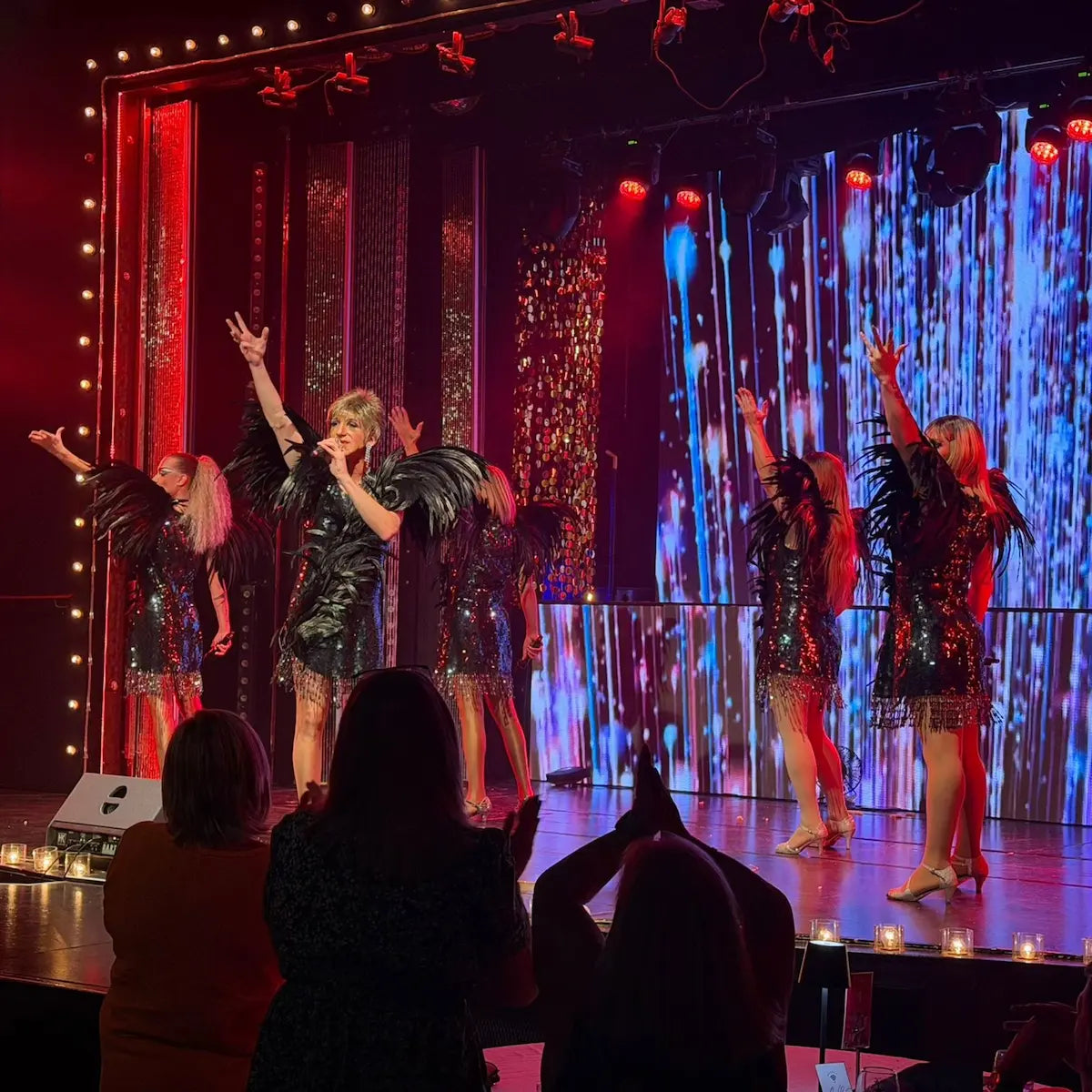 Performers on stage with colorful lights and a digital backdrop