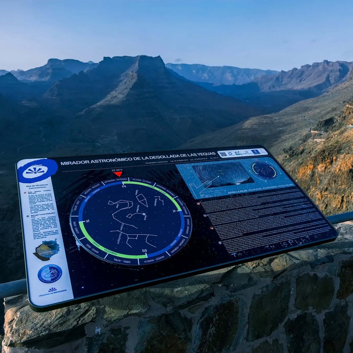 Information board at the astronomical viewpoint in Gran Canaria with star maps and surrounding mountains.