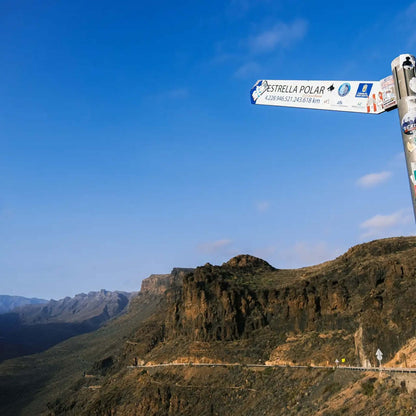 Signpost pointing towards Estrella Polar against a scenic Gran Canaria landscape.