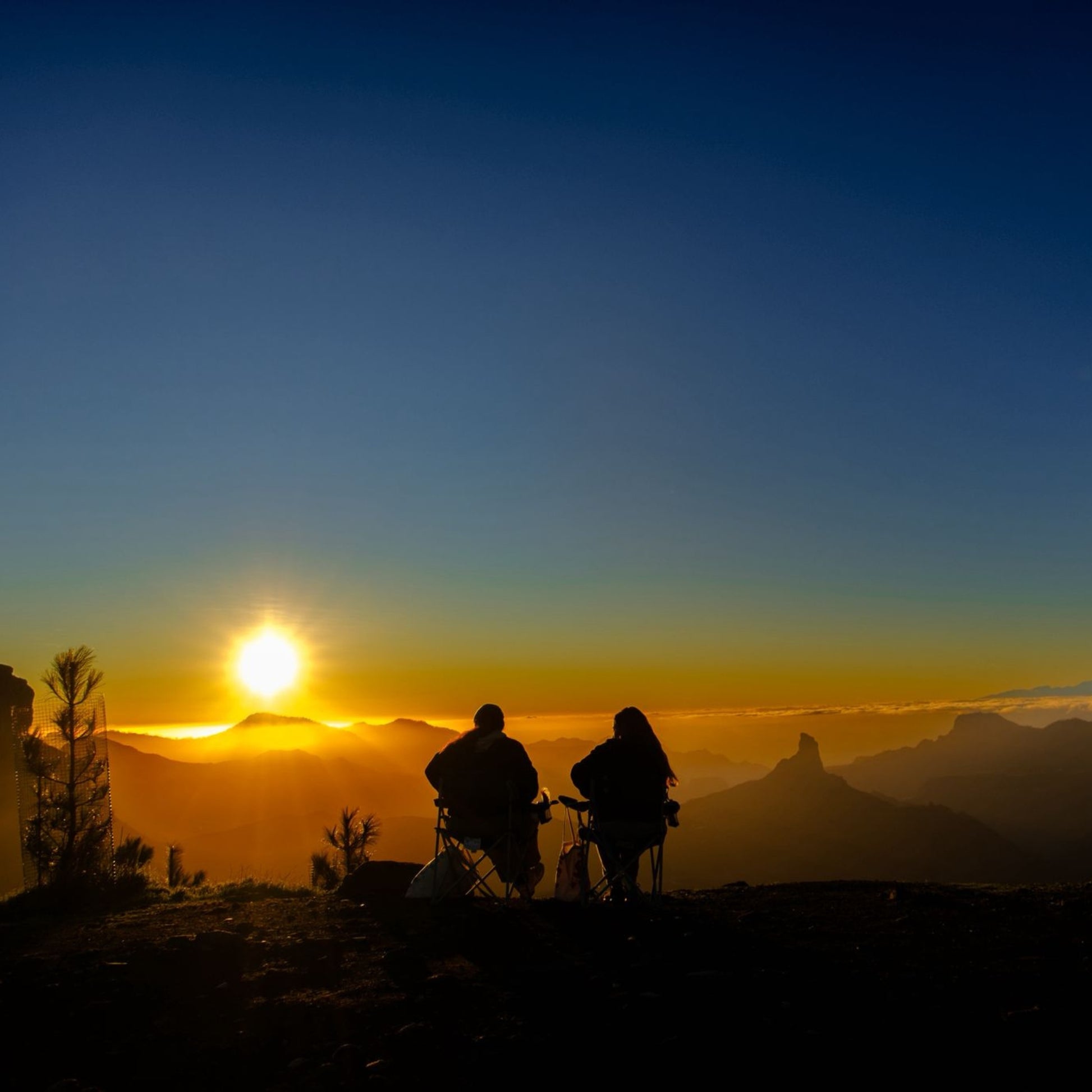 Sunset & stargazing tour in Gran Canaria: Two people sitting on a mountain top watching the sunset.