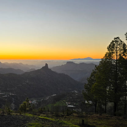Mountain landscape in Gran Canaria with warm light over a valley, Roque Nublo in the foreground and Tenerife on the horizon.