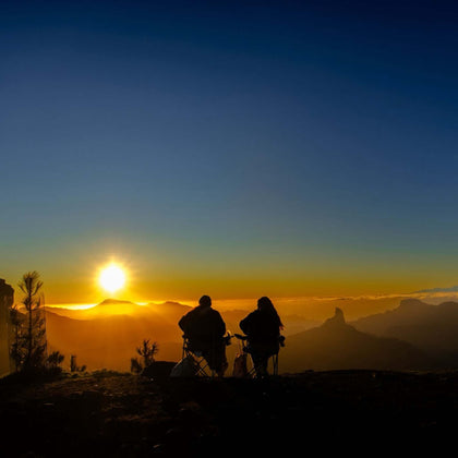 Sunset & stargazing tour in Gran Canaria: Two people sitting on a mountain top watching the sunset.